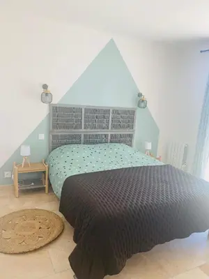 a bedroom with a large bed with a gray headboard at La Maison d à côté 8 à 10 personnes in Carpentras