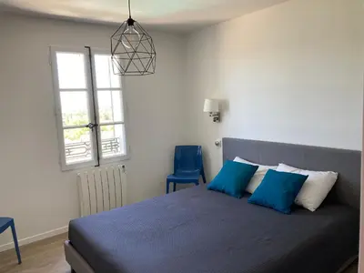 a bedroom with a bed with blue pillows and a window at La bastide in Malemort-du-Comtat