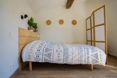 a bedroom with a bed with a blue and white blanket at Petite maison de charme au cœur du centre ville in Apt