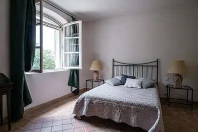 a bedroom with a bed and two windows at Propriété d'exception au coeur du Luberon in Robion en Luberon