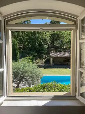 an open window with a view of a yard at Propriété d'exception au coeur du Luberon in Robion en Luberon