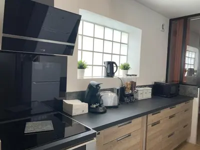 a kitchen with a black counter top and a window at A l'ombre de l'Olivier Spacieux Clim Parking Cosy in LʼIsle-sur-la-Sorgue