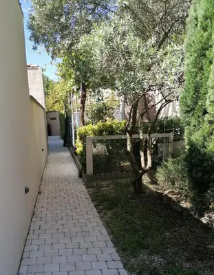 a walkway in a yard with trees and bushes at A l'ombre de l'Olivier Spacieux Clim Parking Cosy in LʼIsle-sur-la-Sorgue
