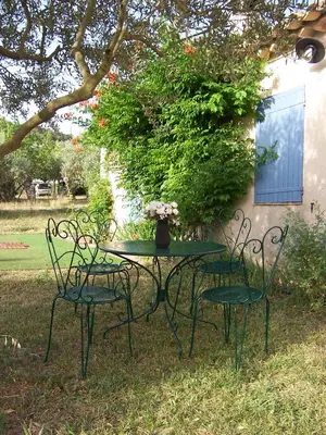 a table and two chairs with a vase on it at OUSTAOU DU GAYET gîte de charme avec piscine privée in Lourmarin