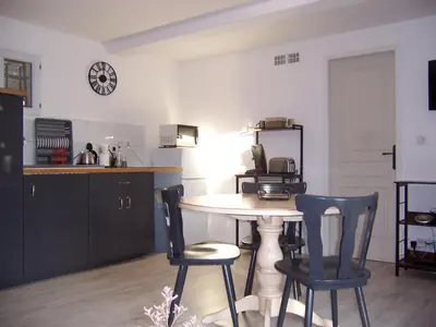 a kitchen with a table and chairs and a clock on the wall at OUSTAOU DU GAYET gîte de charme avec piscine privée in Lourmarin