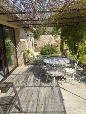 a patio with a table and chairs on a deck at Gîte Les Rapières in Gordes