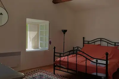a bedroom with a bed with a red sheets and a window at La Maison de la Forge in Gordes