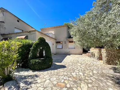 a house with a large bush in front of a driveway at Maison Provençale avec piscine in Carpentras