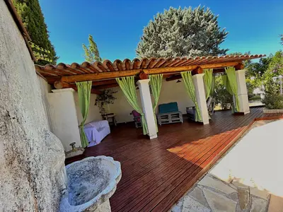 a wooden deck with a pergola and a table at Maison Provençale avec piscine in Carpentras