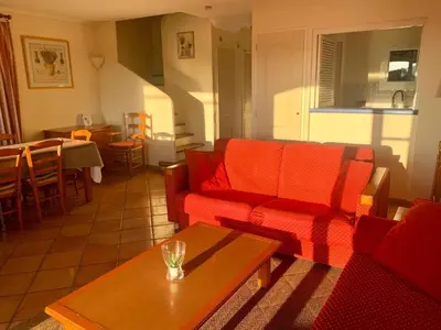 a living room with a red couch and a table at Les Maisons de Pont Royal en Provence - maeva Home - Maison climatisée pour 8 Personnes avec jardin privatif et terrasse MAE-2283 in Mallemort