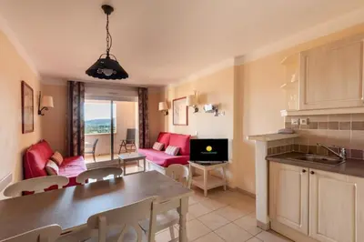 a kitchen and living room with red chairs and a table at Les Coteaux de Pont Royal en Provence - maeva Home - Appartement 2 Pièces 4 Personnes - Confort MAE-5993 in Mallemort