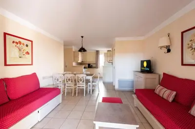 a living room with red couches and a kitchen at Les Coteaux de Pont Royal en Provence - maeva Home - Appartement 3 Pièces 6 Personnes - Sélection MAE-6001 in Mallemort