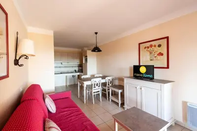 a living room with a red couch and a kitchen at Les Coteaux de Pont Royal en Provence - maeva Home - Appartement 2 Pièces 4 Personnes - Confort MAE-6002 in Mallemort