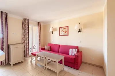 a living room with a red couch and a table at Les Coteaux de Pont Royal en Provence - maeva Home - Appartement 2 Pièces 4 Personnes - Sélection MAE-6017 in Mallemort
