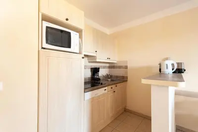 a small kitchen with white cabinets and a microwave at Les Coteaux de Pont Royal en Provence - maeva Home - Appartement 2 Pièces 4 Personnes - Sélection MAE-6017 in Mallemort