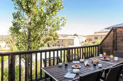 a table on a balcony with a view of a city at Les Coteaux de Pont Royal en Provence - maeva Home - Appartement climatisé 2 Pièces 4 Personnes - Sélection MAE-6022 in Mallemort