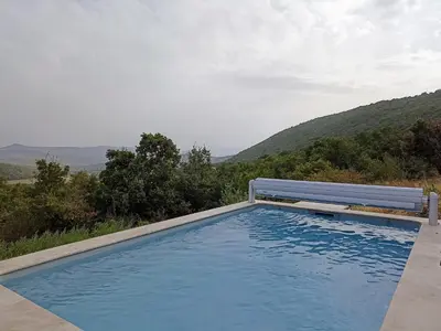 a blue swimming pool with a bench next to it at Gite avec piscine 