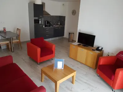 a living room with two red chairs and a television at Domitys Les Cigales du Lubéron in Cavaillon