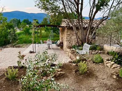 a garden with a table and chairs and a house at Cabanon bucolique face au Luberon in Lourmarin