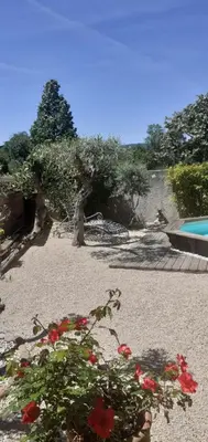 a garden with red flowers and a swimming pool at Location saisonnière avec piscine et terrasse au pied du luberon in Lauris