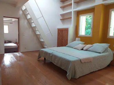 a bedroom with a bed in a room with stairs at maison au coeur de Fontaine de Vaucluse, nichée sur le rocher et surplombant la sorgue in Fontaine-de-Vaucluse