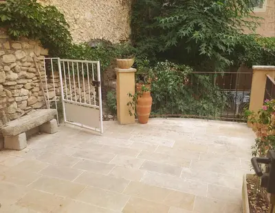 a patio with a gate and a stone wall at maison au coeur de Fontaine de Vaucluse, nichée sur le rocher et surplombant la sorgue in Fontaine-de-Vaucluse