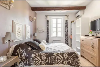 a bedroom with a bed and a dresser and a television at Douceur sur la Sorgue in LʼIsle-sur-la-Sorgue