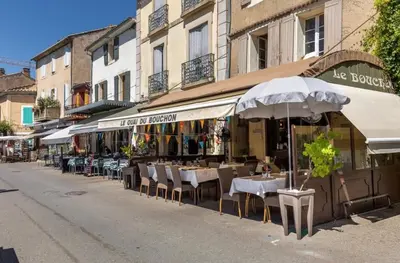 an outdoor restaurant with tables and chairs and umbrellas at Douceur sur la Sorgue in LʼIsle-sur-la-Sorgue