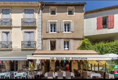a building with tables and chairs in front of a building at Douceur sur la Sorgue in LʼIsle-sur-la-Sorgue