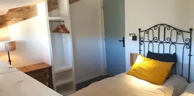 a bedroom with a bed with a yellow pillow on it at Logement calme avec vue sur le Luberon in Saignon