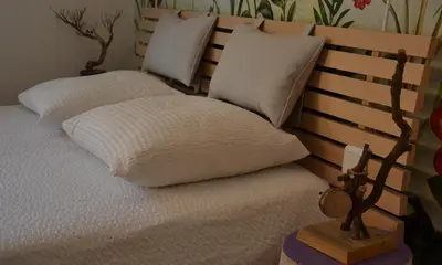 a bed with white pillows and a wooden head board at Le gîte du petit branché in Mazan