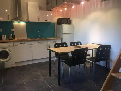 a kitchen with a table and chairs and a refrigerator at 2 pièces et mezzanine dès 2 nuits in Vedène