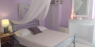 a bedroom with a bed with purple walls and a window at Bienvenue à la Source dans une Maison de Charme in Apt