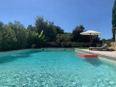 a swimming pool with an umbrella and a red boat in it at Le Domaine de l'Aiguille Alpilles, Eygalières, Saint Rémy de Provence in Orgon