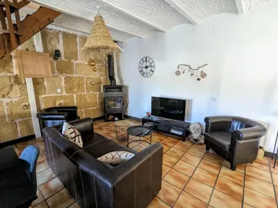 a living room with leather furniture and a stone wall at La ferme du TourreBlanc in Lambesc