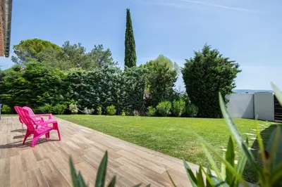 a pink chair sitting on a wooden deck in a yard at Les Villas des Fontaines in Saumane-de-Vaucluse