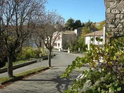 an empty street in a village with trees and houses at Maison accueillante à Reillanne avec jardin clos in Reillanne