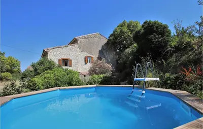 a swimming pool in front of a stone house at 2 Bedroom Beautiful Home In St Didier in Saint-Didier