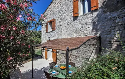 a table and chairs in front of a stone building at 2 Bedroom Beautiful Home In St Didier in Saint-Didier