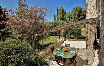 a table and chairs sitting under a wooden archway at 2 Bedroom Beautiful Home In St Didier in Saint-Didier