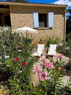 a patio with two chairs and an umbrella and flowers at Le Mas de Caroline in Gargas