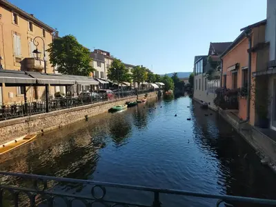 a canal in a city with boats in the water at Gîte Les Demoiselles des Sorgues in LʼIsle-sur-la-Sorgue