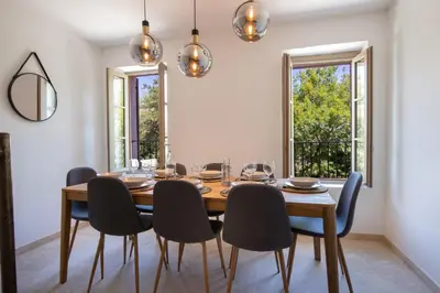 a dining room with a table and chairs and windows at Au NÈGO CHIN 105m2 en bord de Sorgue in LʼIsle-sur-la-Sorgue