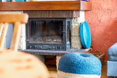 a living room with a fireplace and a chair at Au petit bonheur in Bédoin