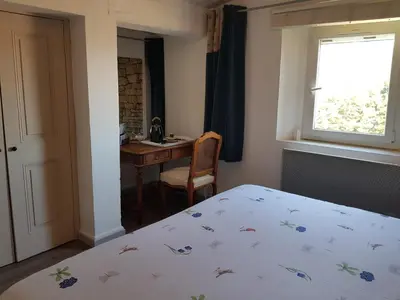 a bedroom with a bed and a desk and a window at Chambre du sentier des ocres in Roussillon