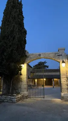 a gate to a stone building with a tree at Domaine de la Reynaude in Aurons