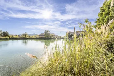 a view of a river with grass and buildings at Village Pont Royal en Provence - maeva Home - Appartement 2 pièces 5 personnes - Sélection MAE-8624 in Mallemort