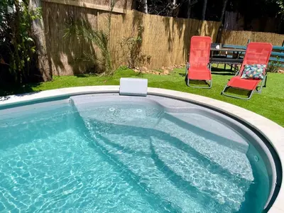 a swimming pool with two chairs and a table at Calme et Intimité proche Avignon Piscine options au choix privée ou partagée de juin à octobre in Morières-lès-Avignon