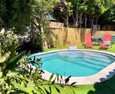 a small pool in a yard with two red chairs at Calme et Intimité proche Avignon Piscine options au choix privée ou partagée de juin à octobre in Morières-lès-Avignon
