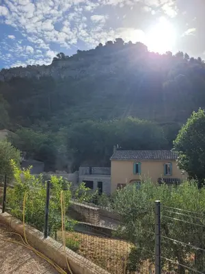 a house in front of a mountain with the sun at L'Oustau de Laëtitia Animaux bienvenus in Fontaine-de-Vaucluse
